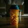 A prescription bottle filled with yellow pills on a wooden table.