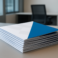 Stack of printed materials with a blue cover on a desk