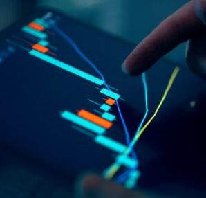 Close-up of a hand pointing at a stock market graph on a tablet screen