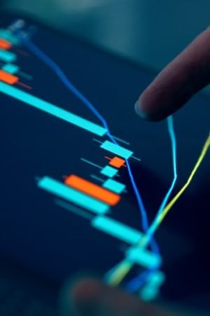 Close-up of a hand pointing at a stock market graph on a tablet screen