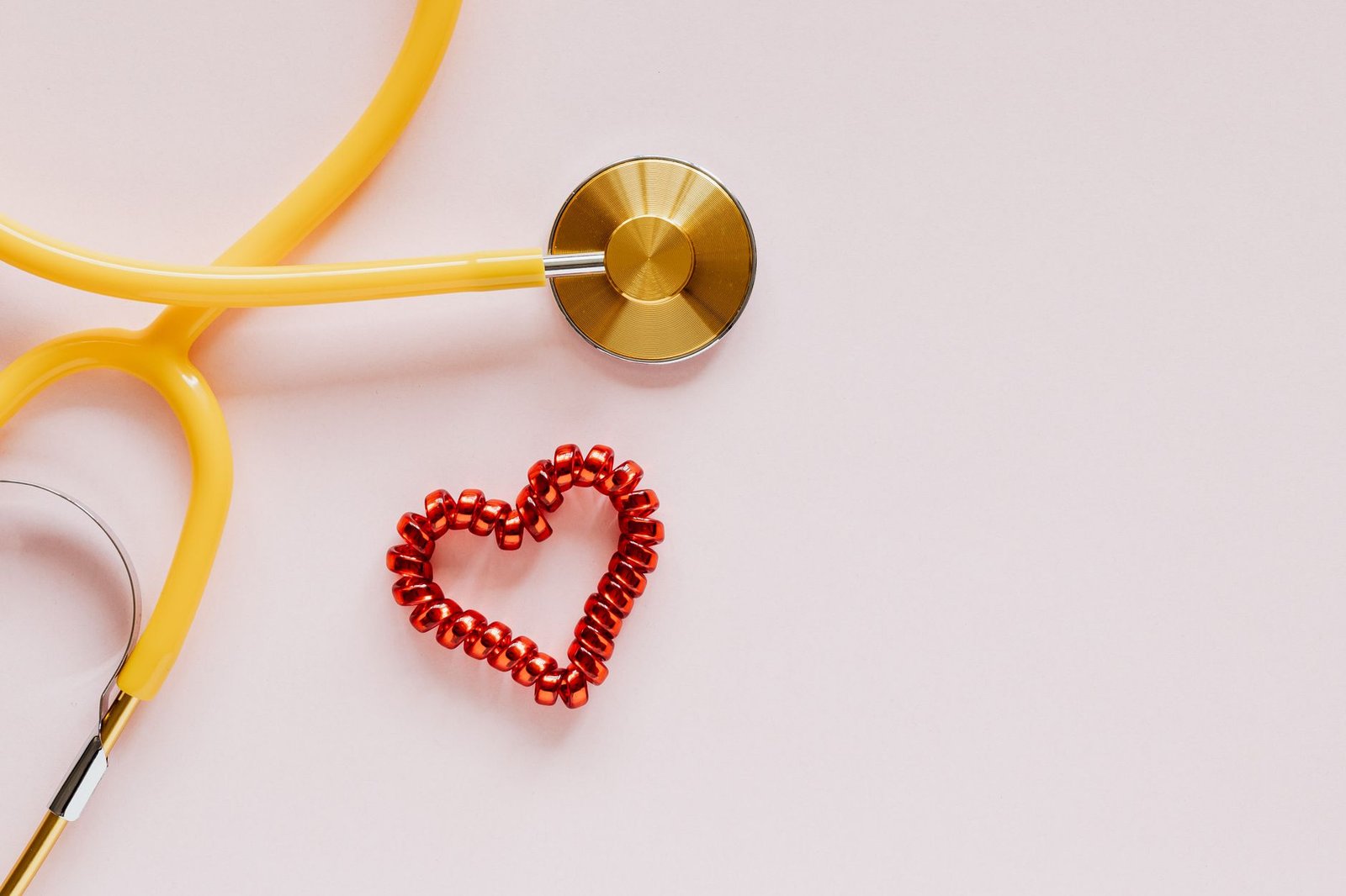 From above of yellow stethoscope near small red bead heart made for San Valentines Day on pale pink surface — 10 Reasons to T