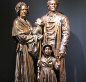 Bronze sculpture of a family with historical clothing, depicting a father, mother, and two children.
