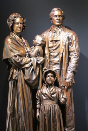 Bronze sculpture of a family with historical clothing, depicting a father, mother, and two children.