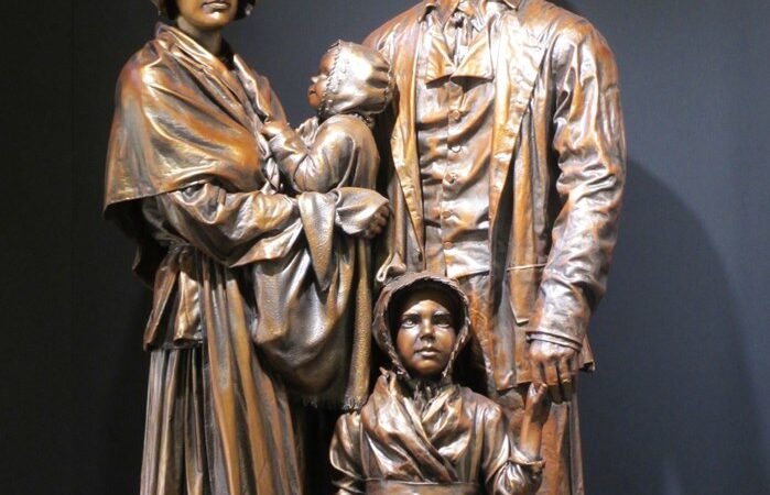 Bronze sculpture of a family with historical clothing, depicting a father, mother, and two children.