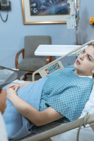 Caucasian woman in hospital bed receiving care from healthcare professional. — Fighting Weight Gain After Pregnancy Like Tess