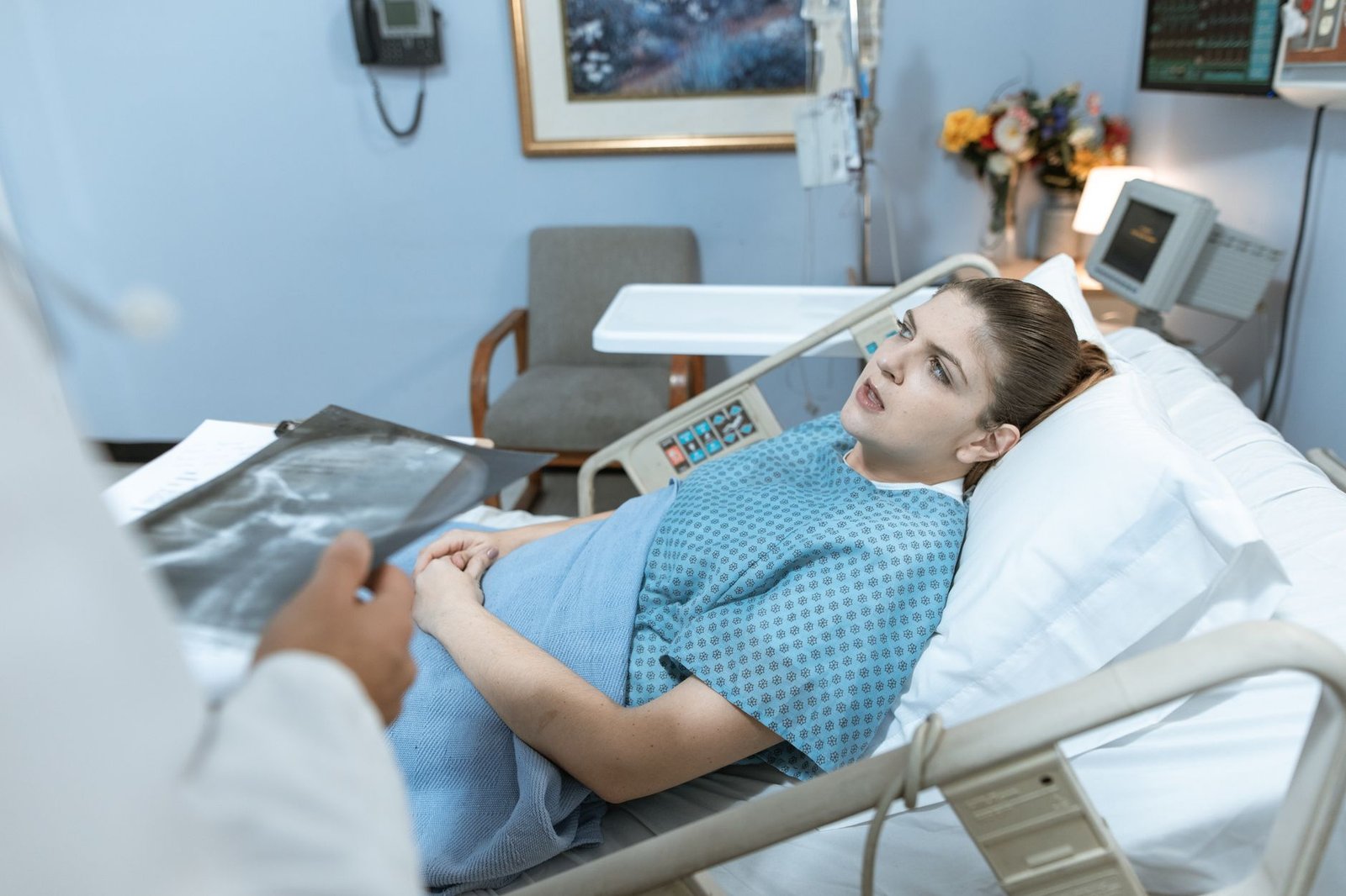 Caucasian woman in hospital bed receiving care from healthcare professional. — Get relief from the chronic pain in your wrist