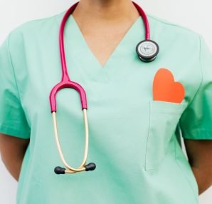 Close-up of a medical professional with a stethoscope and a paper heart cutout on a green uniform pocket. — Importance of Pre