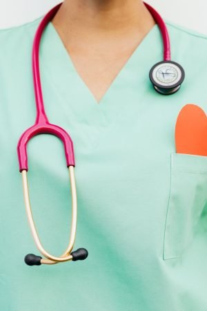 Close-up of a medical professional with a stethoscope and a paper heart cutout on a green uniform pocket. — Importance of Pre