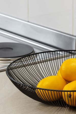 Lemons in a metal bowl on a kitchen counter beside an electric stove, highlighting freshness and simplicity. — Live Boxing Ma