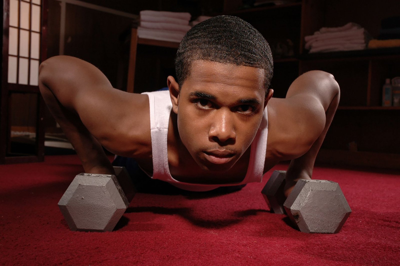 A determined male athlete exercising with dumbbells indoors on a red carpet. — MinnesotaCare Offers Minnesota Health Insuranc