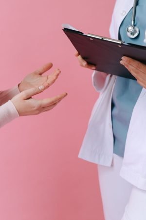 Close-up of a patient consulting a doctor with a clipboard in a medical setting. — Reasons Why to Hire Personal Trainer for T