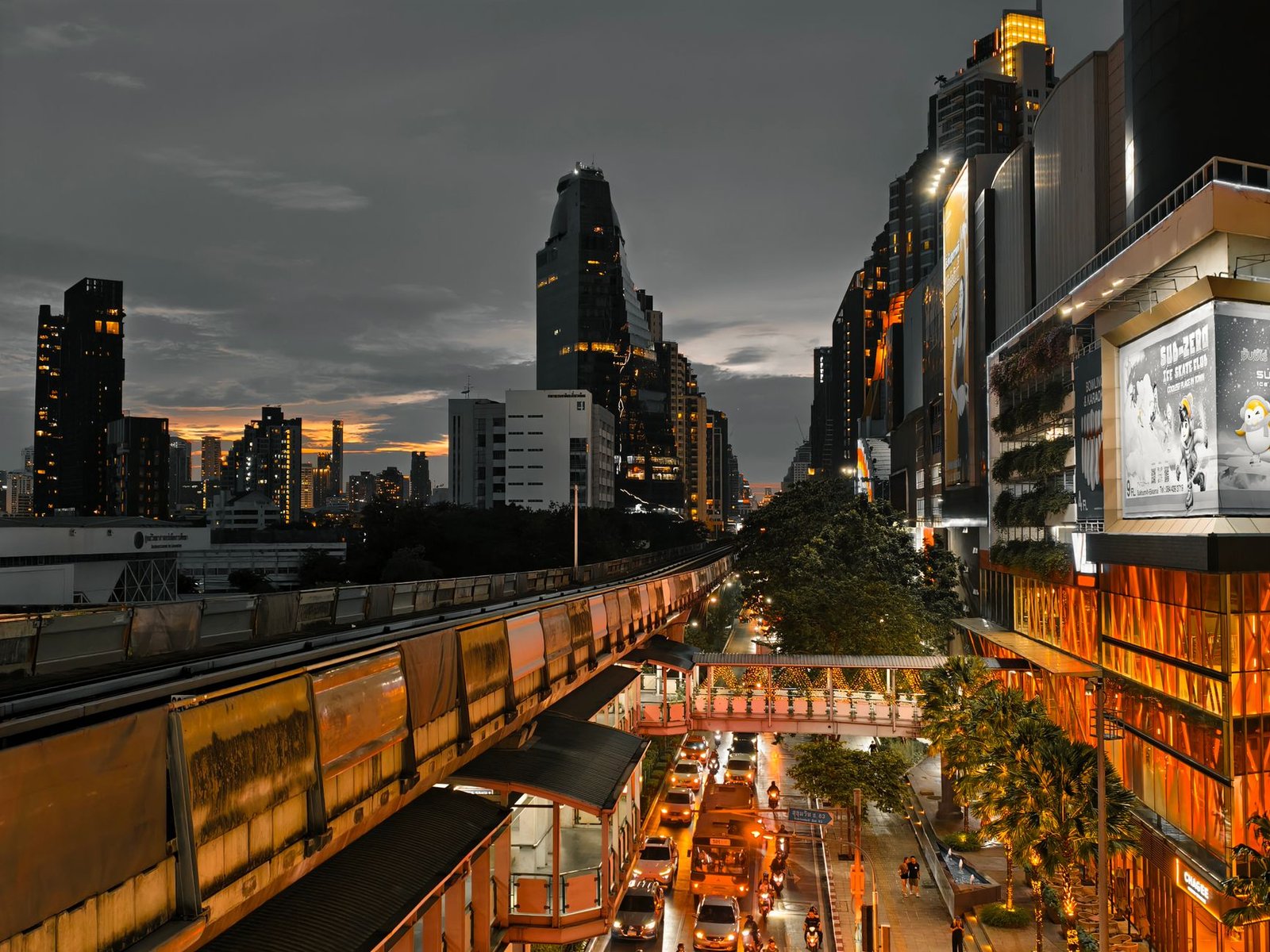 Cityscape at twilight showing busy traffic, skyscrapers, and an elevated train line in an urban setting. — What It's Like to