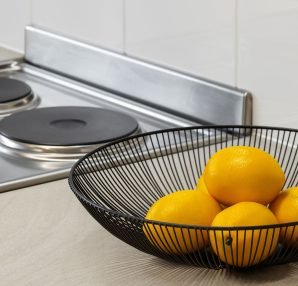 Lemons in a metal bowl on a kitchen counter beside an electric stove, highlighting freshness and simplicity. — Why Combine Mi