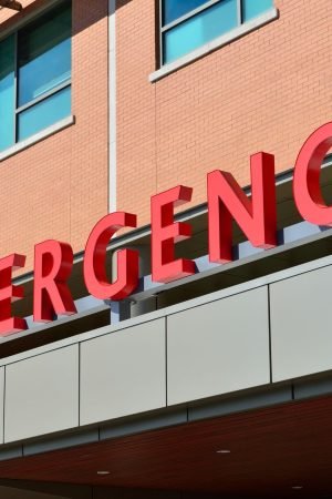 Close-up of a modern hospital emergency room entrance with prominent red letters. — Why is Onsite TB Testing Done?