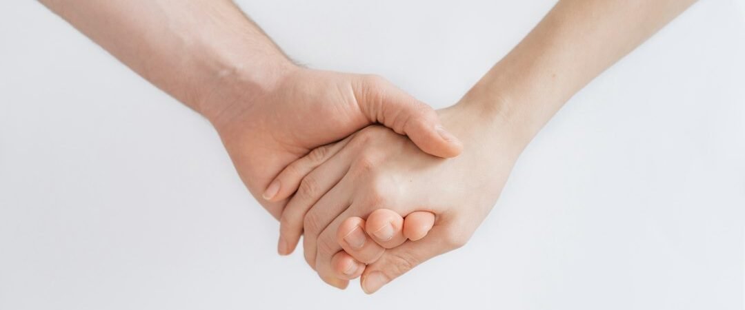 two hands clasped together against a plain background