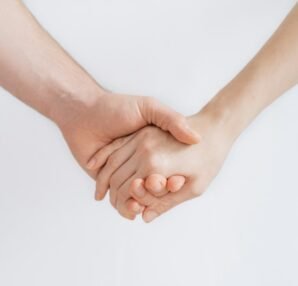 two hands clasped together against a plain background