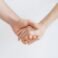 two hands clasped together against a plain background